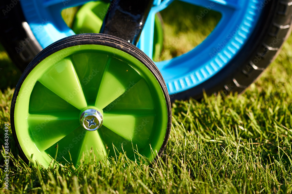 small green helper wheel of the child bicycle on the green grass in the garden Stock Photo