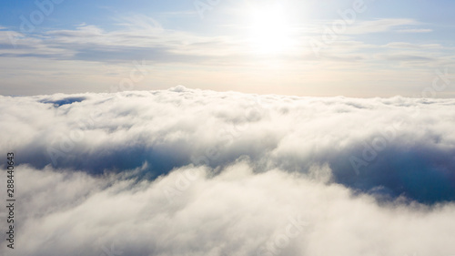 Fototapeta Naklejka Na Ścianę i Meble -  Aerial view White clouds in blue sky. Top view. View from drone. Aerial bird's eye view. Aerial top view cloudscape. Texture of clouds. View from above. Sunrise or sunset over clouds