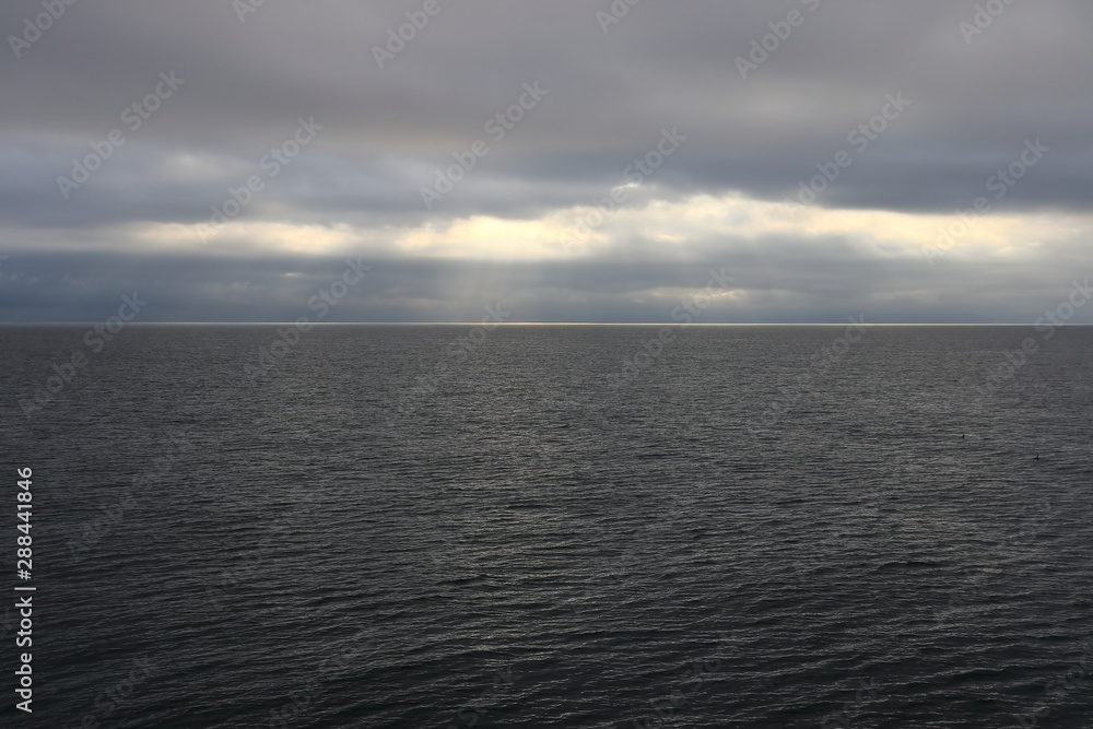 Dark sea and cloudy sky with sun rays lightning through the clouds. Seascape for design template, background or wallpaper. Dark sea and cloudy sky with sun rays lightning through the clouds. Seascape for design template, background or wallpaper.