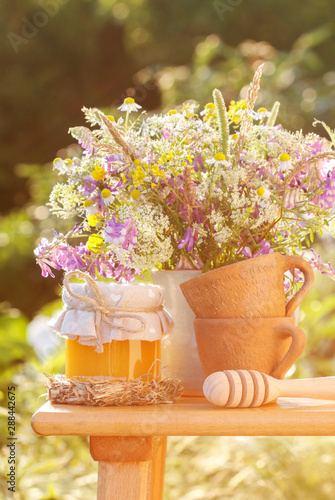 Fototapeta Naklejka Na Ścianę i Meble -  Jars with honey and bouquet of wild flowers in the garden.