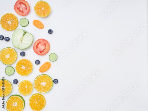 Fresh fruits and vegetables sliced on white background