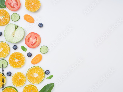 Fresh fruits and vegetables sliced on white background