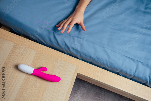 Photos woman and man reaches for the bedside table for sex toy
