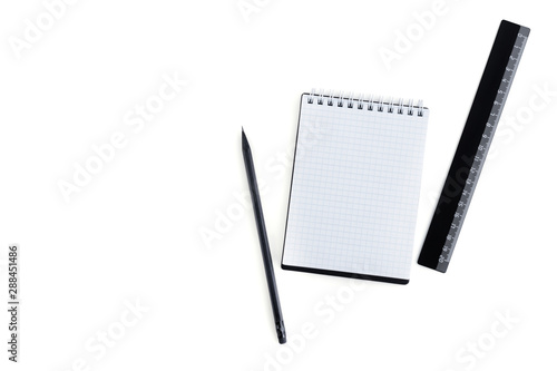 Flat lay composition of an open notebook with checkered sheets, a black pencil and a black ruler with an empty place for text isolated on white background