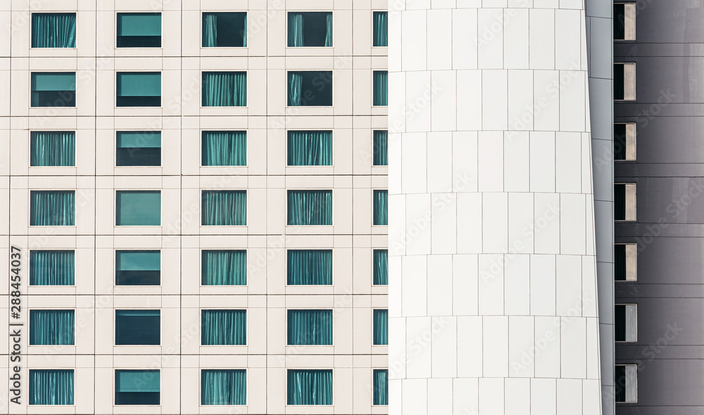 Modern building facade with window glasses sky color reflected and some lighted from the inside with white iron cladding building skin. Modern building facade with window glasses sky color reflected and some lighted from the inside with white iron cladding building skin.