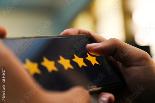 attractive hands giving five stars rating on a smart phone