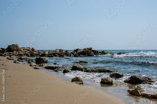 Beautiful wild beach landscape, sunny day, water waves hitting the cliffs, nature summertime scene © Len0r