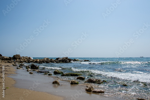 Beautiful wild beach landscape, sunny day, water waves hitting the cliffs, nature summertime scene