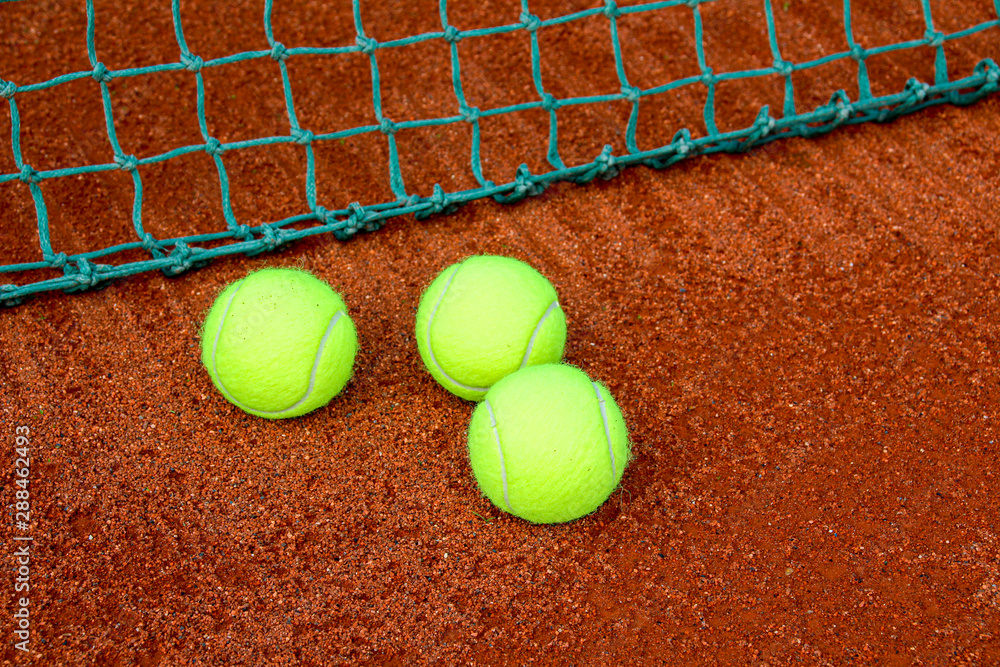 three yellow tennis balls on a tennis court