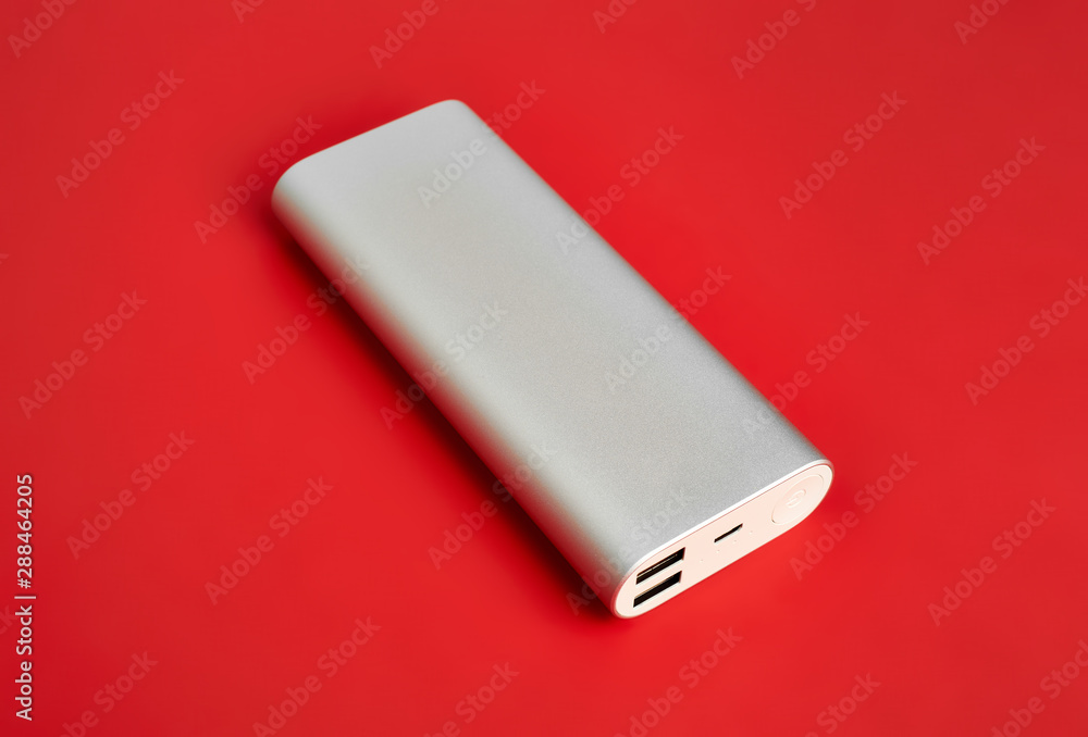 Power bank for charging mobile devices. White smart phone charger with power bank. Battery bank on a red background . External battery for mobile devices. Power bank for charging mobile devices. White smart phone charger with power bank. Battery bank on a red background . External battery for mobile devices.