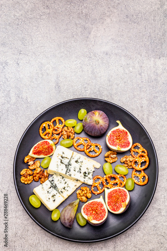Cheese plate with blue cheese, walnuts, figs, grapes, pretzels