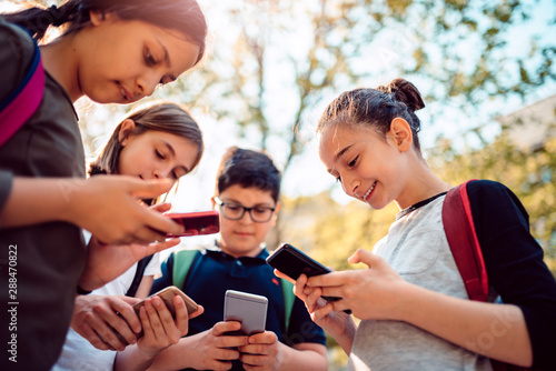 Kids playing video games on smart phone after school photo