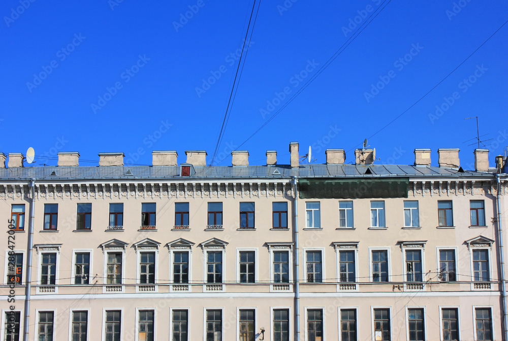 House facade with classic simple architecture details on city street. Close up of old town building structure on blue sky background in Saint Petersburg, Russia 
