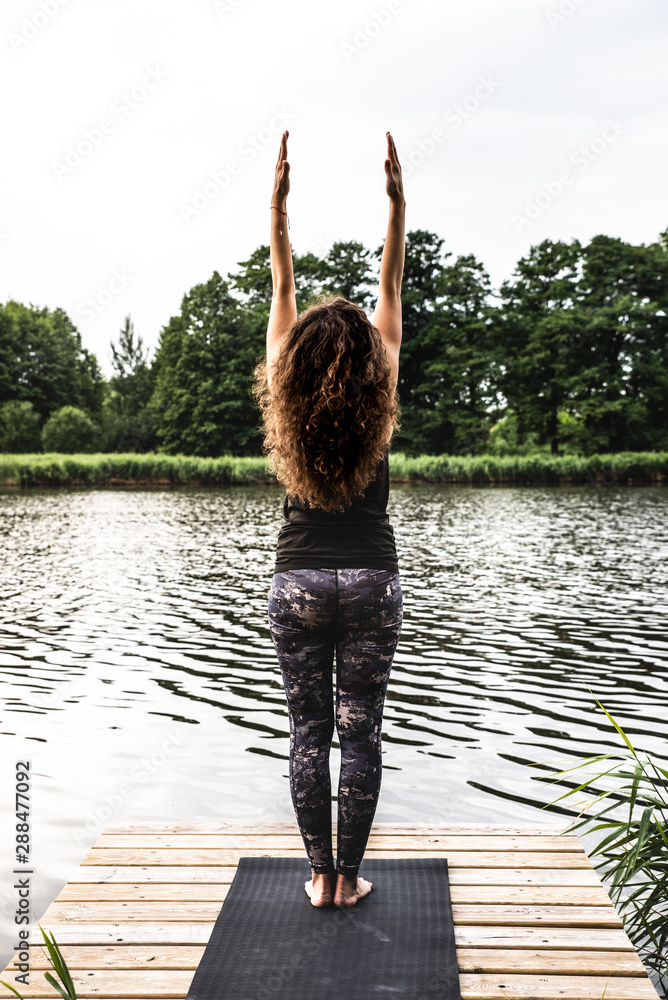 Dziewczyna w pozycji jogi ćwiczy nad jeziorem. Powitanie słońca.  - obrazy, fototapety, plakaty 