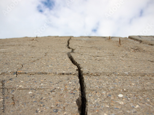 Obraz na plátne Crack in Concrete Wall with Cloudy Sky