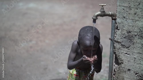 Handsome Little African Baby Boy Drinking Fresh Water under the Sun photo