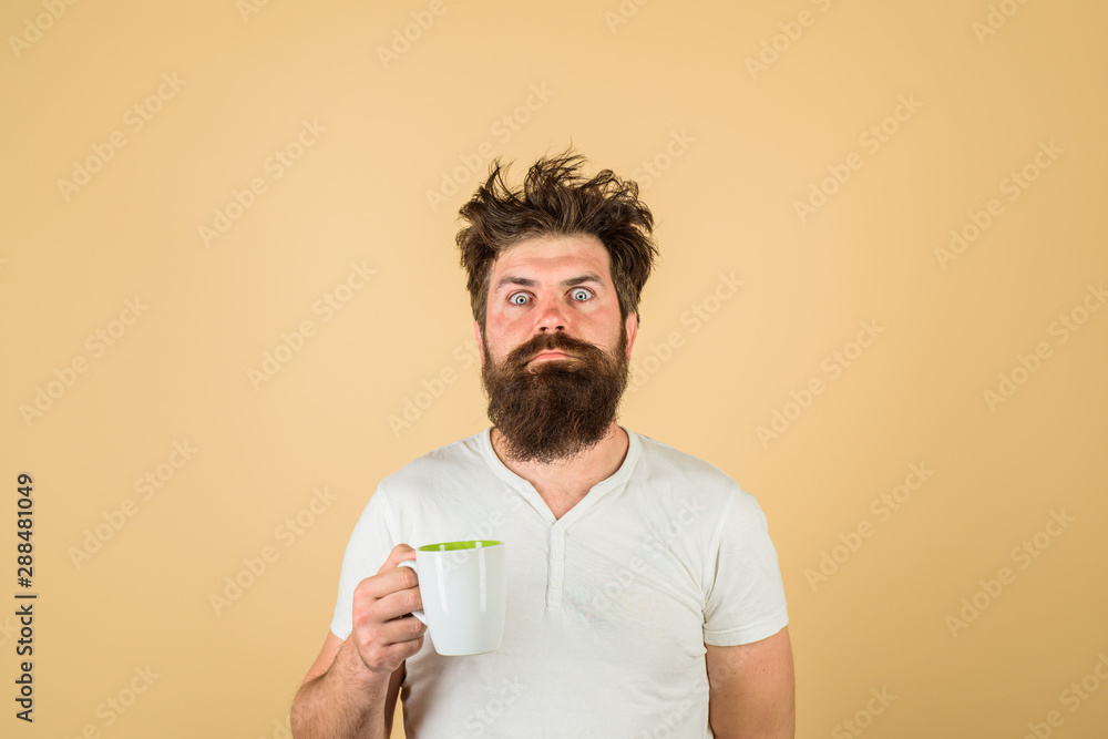 Sleepy guy with cup of tea or coffee. Morning with coffee or milk. Man with sleepy face try to awake with cup of coffee. Sleepy man with beard holds mug in hand. Morning coffee. Breakfast concept. Sleepy guy with cup of tea or coffee. Morning with coffee or milk. Man with sleepy face try to awake with cup of coffee. Sleepy man with beard holds mug in hand. Morning coffee. Breakfast concept.