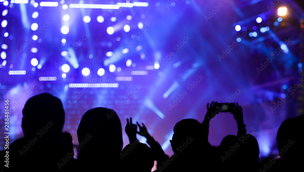 Silhouette hand shoots video on the phone at a rock concert as background