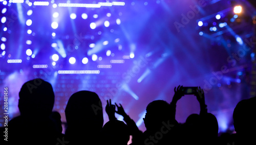 Silhouette hand shoots video on the phone at a rock concert as background