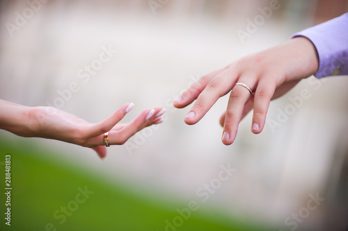 Close-up of the hands of the bride and groom, who touch each other with their fingertips. Close-up