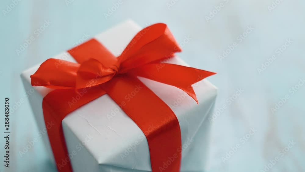 White gift box with red silk ribbon rotating. Gift box for Christmas, black friday and other holidays. Close up 4k footage. White gift box with red silk ribbon rotating. Gift box for Christmas, black friday and other holidays. Close up 4k footage.