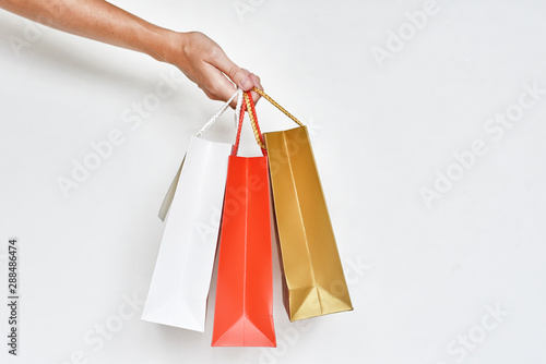 woman hand hold colorful paper shopping bags on a white background, close up