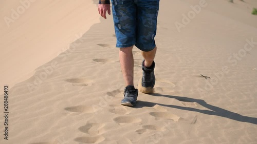 Close-up shot of a man with a running shoe walking through the desert. photo