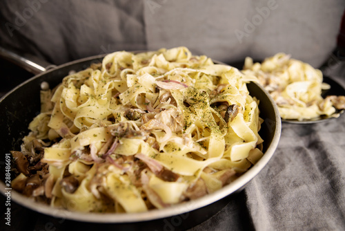 Italian fresh fettuccine pasta with Mushroom and greens in a pan on grey background. top view