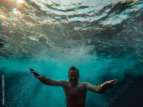 Fotografia, Obraz Underwater photo of man emerging from the water