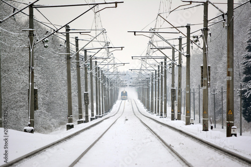 The train is approaching on snow-covered rails and picks up snow dust.