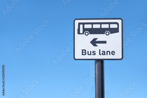 Bus lane symbol sign and direction arrow against blue sky uk
