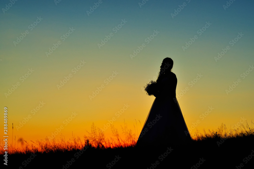 Silhouette of bride against a warm sunset