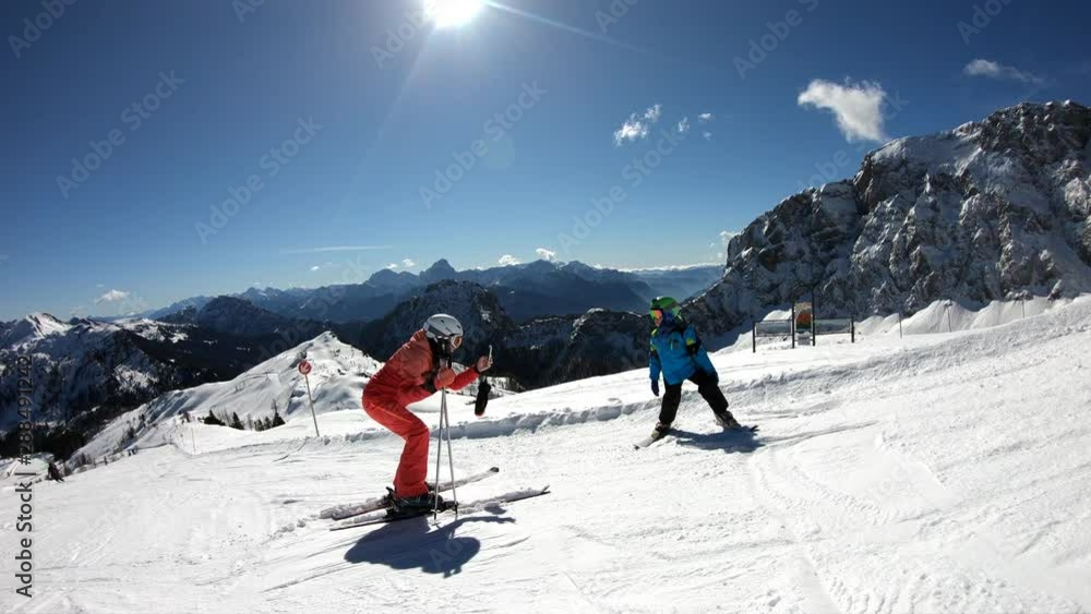 Active holiday winter alps. Mother taking pictures on cell phone of little boy in Austrian Alps. Boy poses while skiing. Active holiday winter alps. Mother taking pictures on cell phone of little boy in Austrian Alps. Boy poses while skiing.