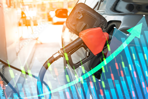 Close up of fuel monitoring system refueling a petroleum to vehicle and graph chart with the indicator on the oil price slide at gas station. Concept fluctuations in oil prices and exchange trade.