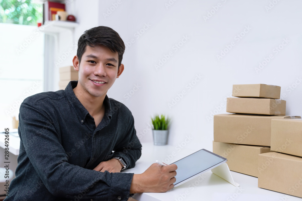 Confident small business owner sitting and taking customer orders by white screen tablet mockup at home office. Confident small business owner sitting and taking customer orders by white screen tablet mockup at home office.