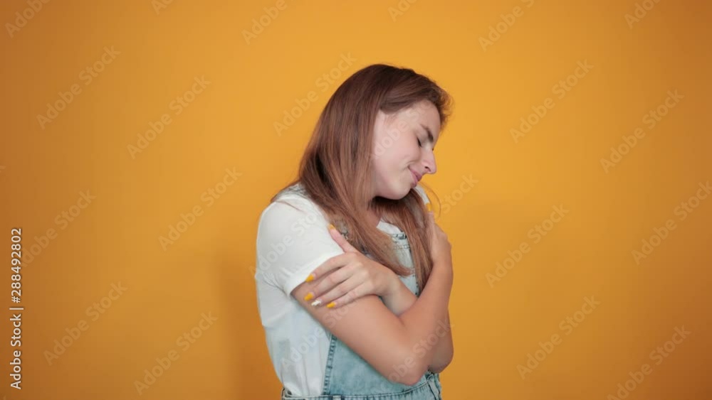 Young woman wearing white t-shirt, over orange background shows emotions Young woman wearing white t-shirt, over orange background shows emotions