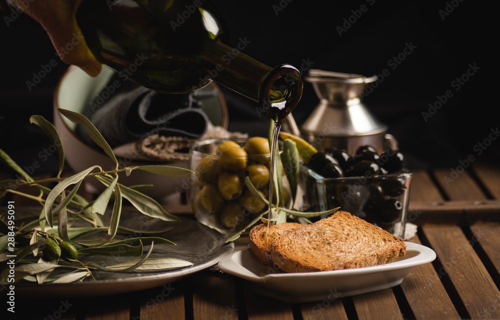 Glass bottle olives and oil falling on bread
