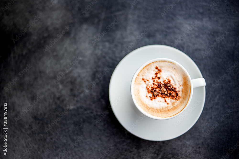Coffee latte or cappuccino in white cup on black table. Top view with empty space for your message. Copy space. Morning ritual, coffee for breakfast. Coffee latte or cappuccino in white cup on black table. Top view with empty space for your message. Copy space. Morning ritual, coffee for breakfast.