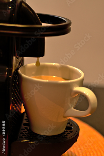 Machine preparing a delicious coffee, next to the capsules.