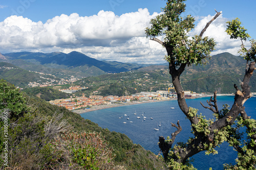 Sestri Ponente, Genoa, Italy. View on Riva Trigoso from Punta Manara. Blue sea with tourist boats. In the background Ligurian mountains with white clouds.