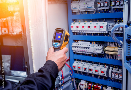Technician use infrared thermal imaging camera to check temperature at fuse-box