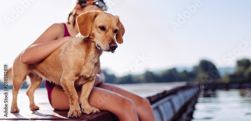 Fototapeta Naklejka Na Ścianę i Meble -  Dog standing on the river dock with girl