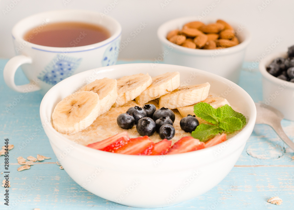 Breakfast. Oatmeal with bananas, strawberries, nuts and blueberries on the blue wooden bakground. Healthy breakfast. Close-up Breakfast. Oatmeal with bananas, strawberries, nuts and blueberries on the blue wooden bakground. Healthy breakfast. Close-up