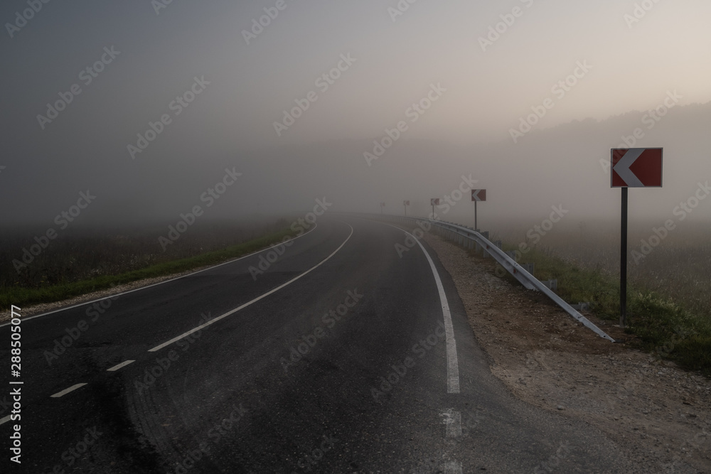 Big road with signs and morning fog