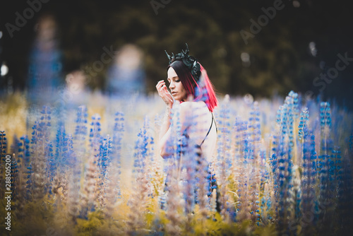 Foto Tätowiertes Model im Maleficent Look zwischen blauen Blumen
