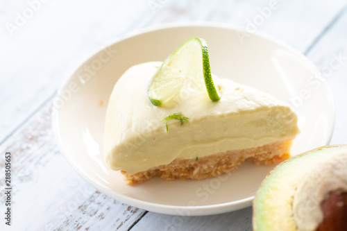 Home made avocado lime cheesecake on a white wood background