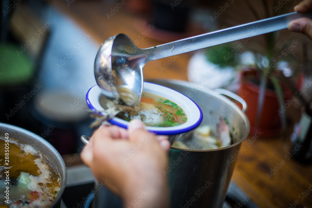 Person serving a portion of fish soup Person serving a portion of fish soup