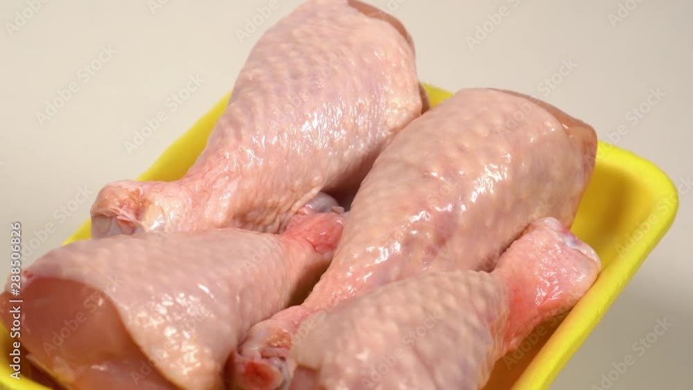 Closeup view of fresh raw uncooked chicken legs laying in plastic container. Closeup view of fresh raw uncooked chicken legs laying in plastic container.