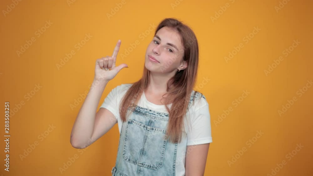 Young woman wearing white t-shirt, over orange background shows emotions Young woman wearing white t-shirt, over orange background shows emotions