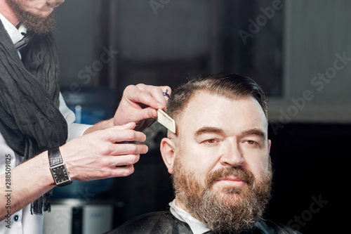 Hairdresser professional shave a man with a beard.